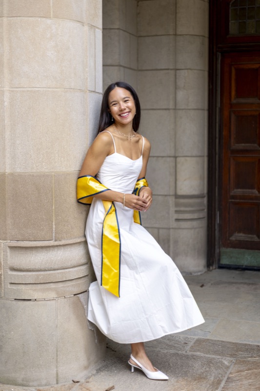 Sophie Chong, smiling, leaning against a stone column